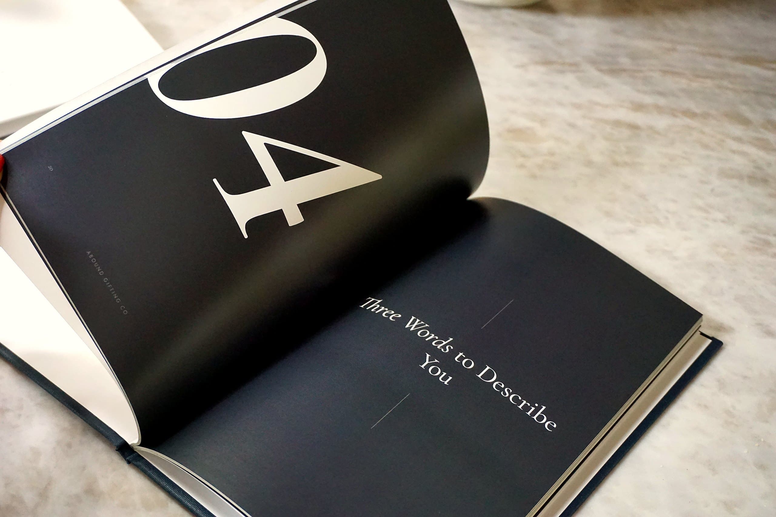 An open Abound custom gift book resting on marble, showing an elegantly typeset spread